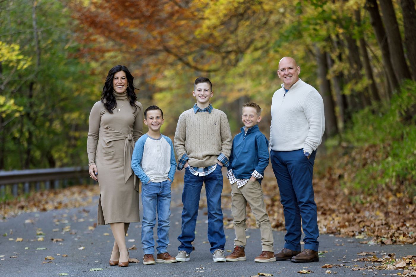 A family is posing for a picture on a road in the woods.