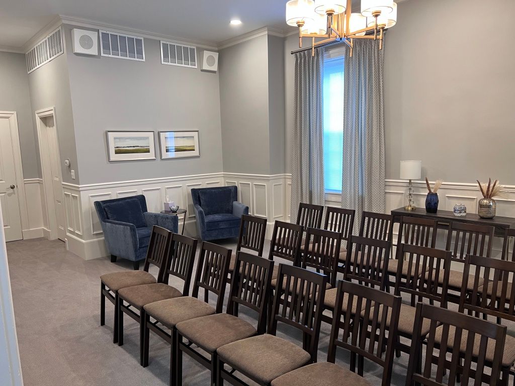 A room with rows of chairs and a chandelier.