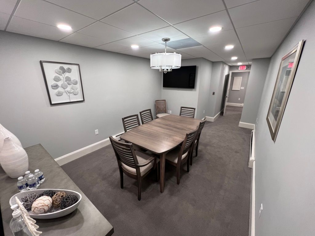A conference room with a table and chairs and a television on the wall.