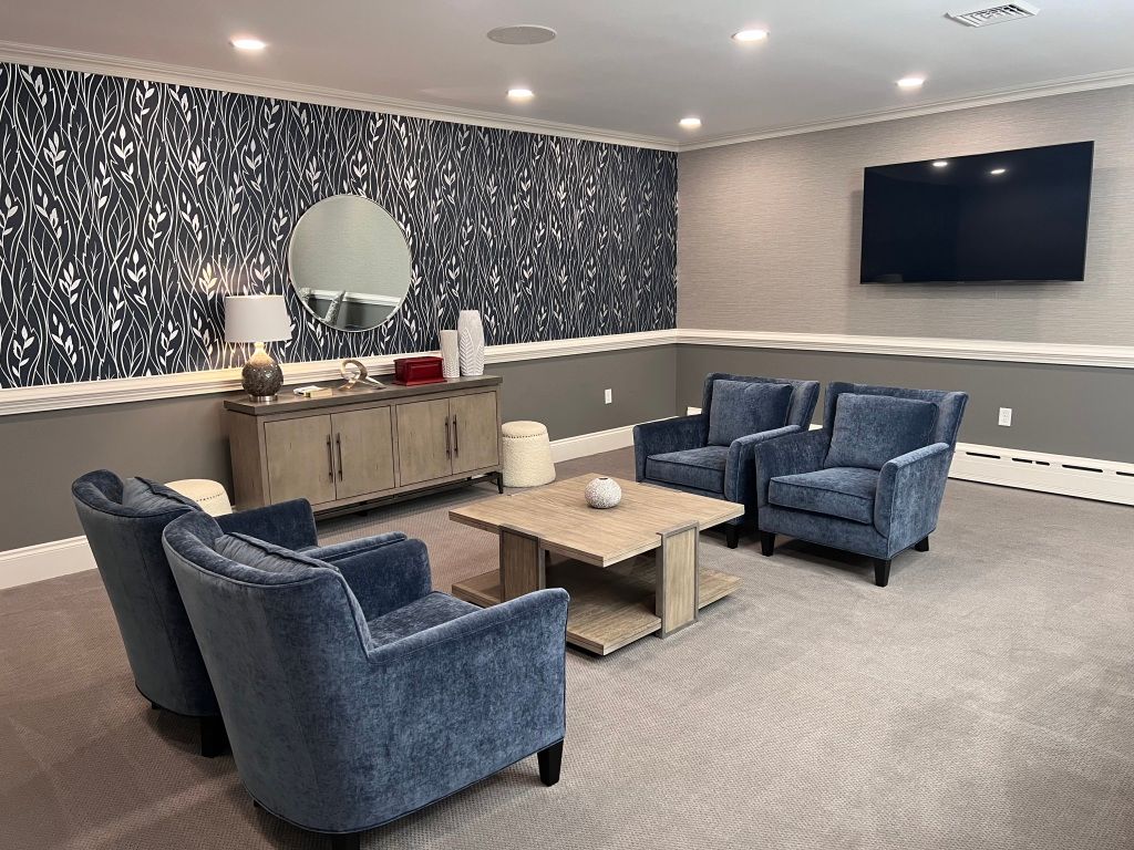 A living room with blue chairs , a coffee table , and a flat screen tv.
