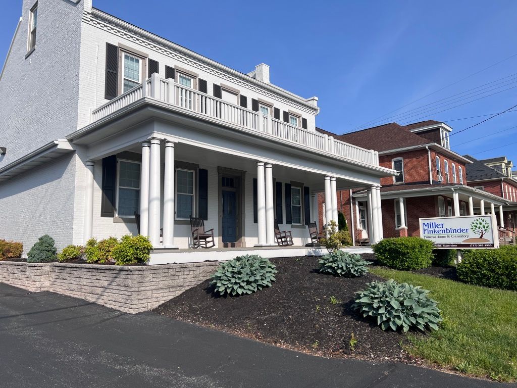 A large white house with black shutters and a large porch.
