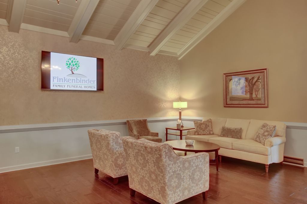 A living room with a couch , chairs , and a flat screen tv.