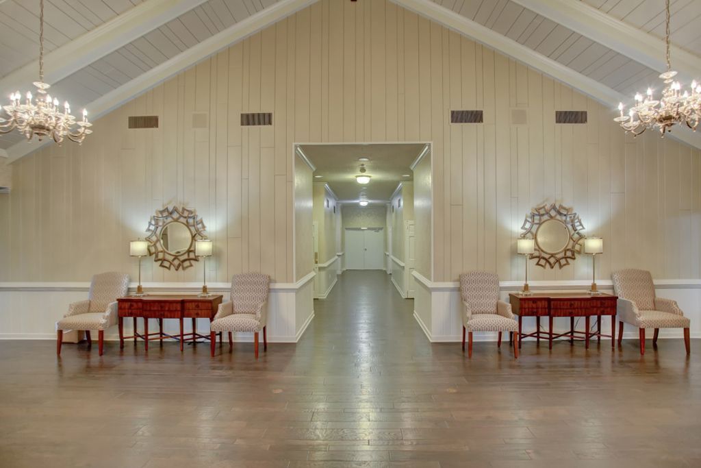 A long hallway with tables and chairs in a large room.