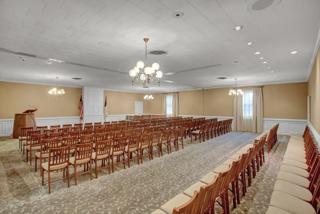 A large room with rows of wooden chairs and a podium.