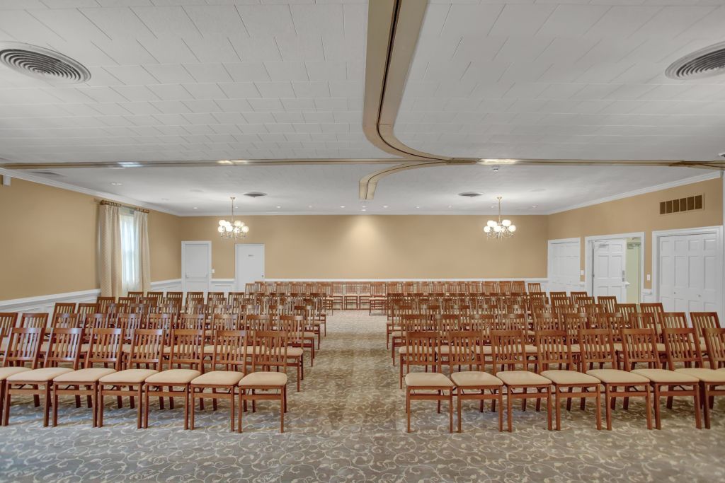 A large room with rows of wooden chairs in it
