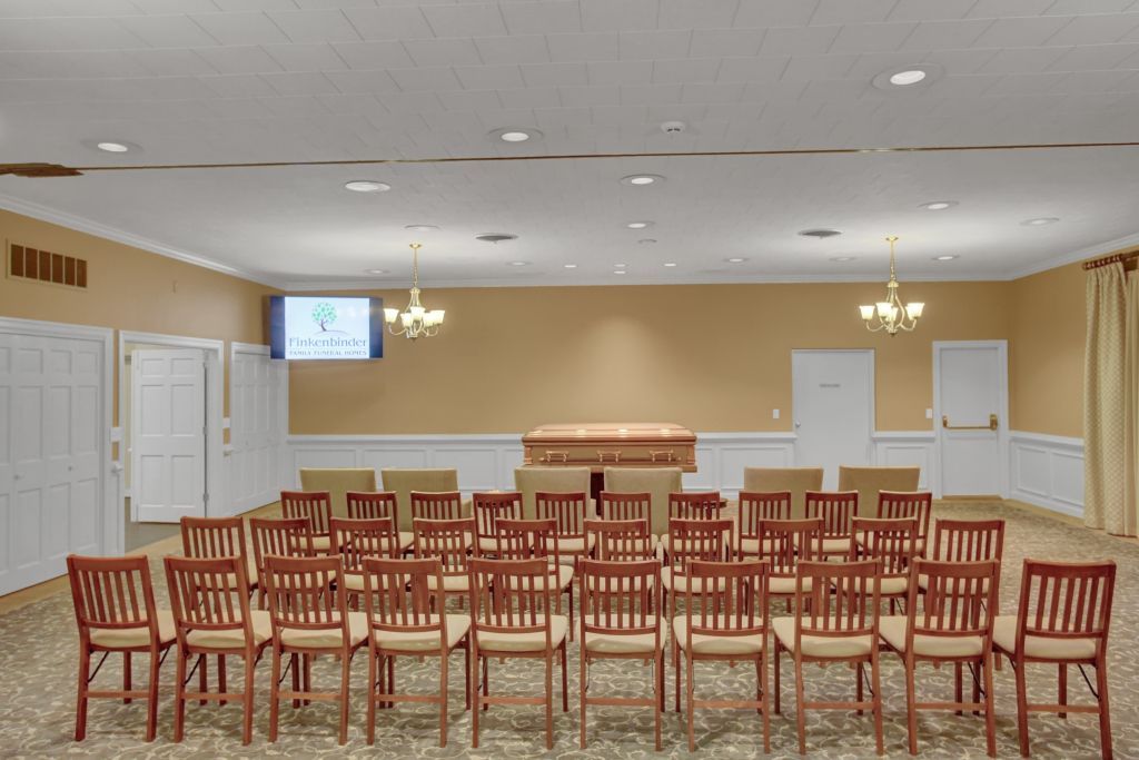 A large room with rows of chairs and a television on the wall.