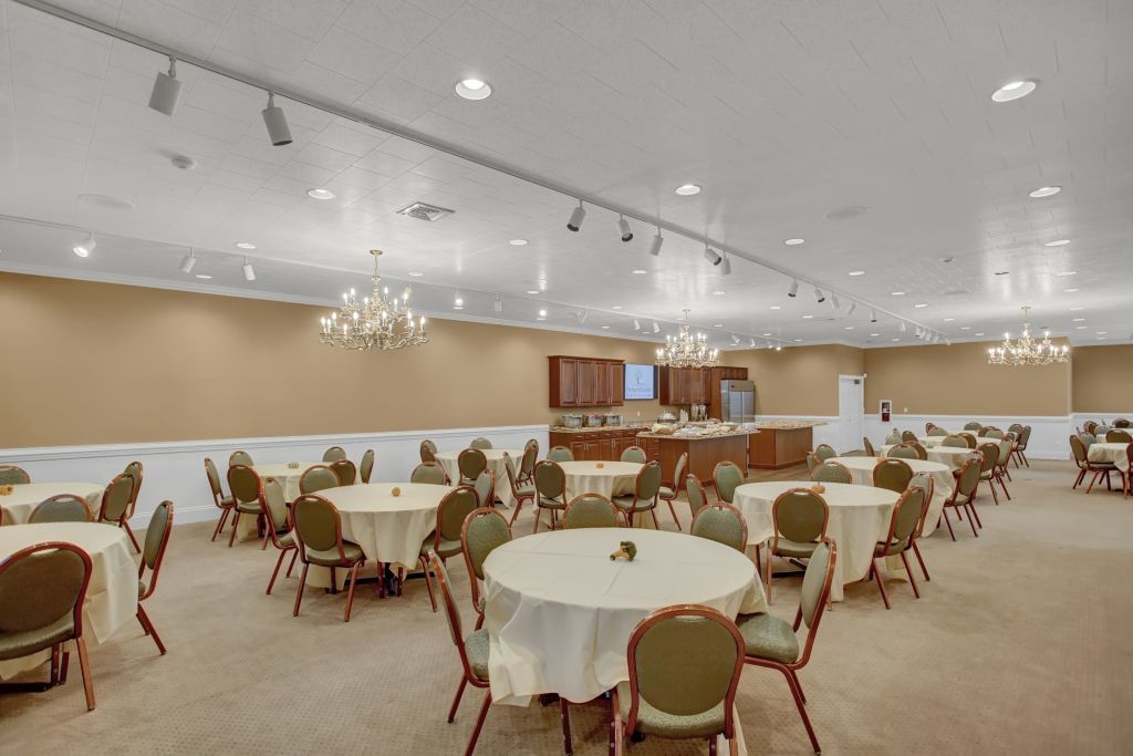 A large room filled with tables and chairs and a chandelier.