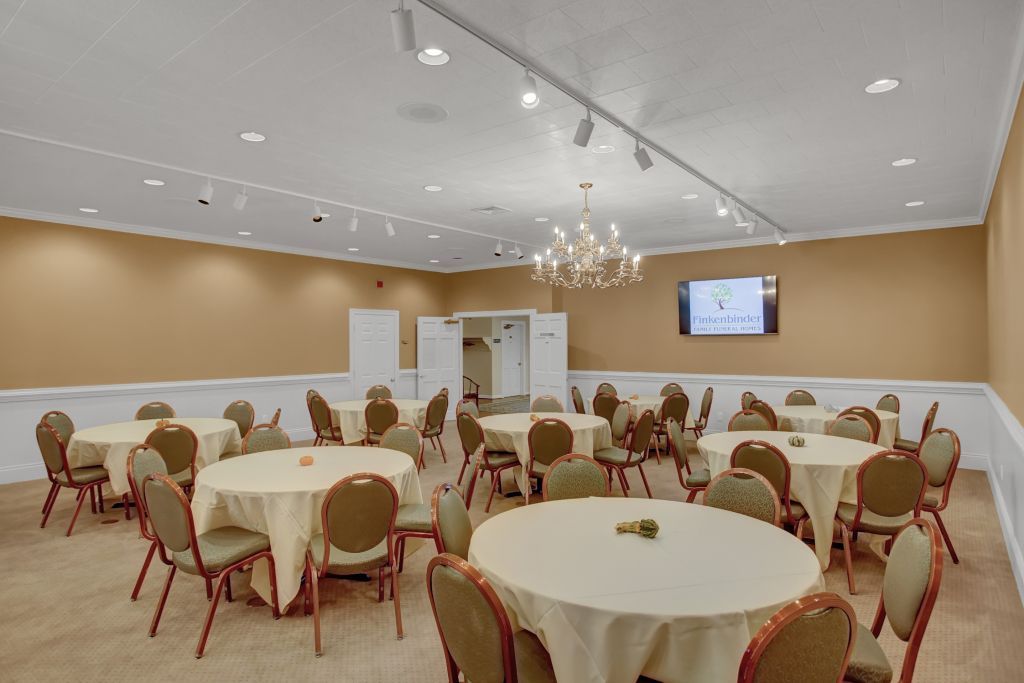 A large room with tables and chairs and a chandelier.