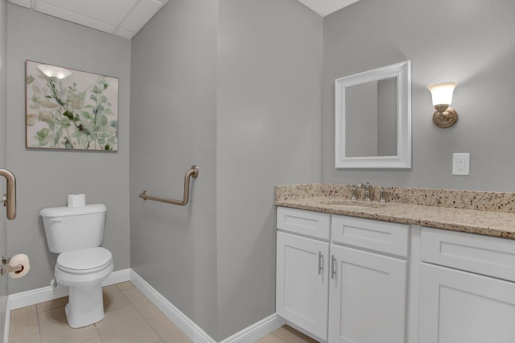 A bathroom with a toilet , sink and mirror.