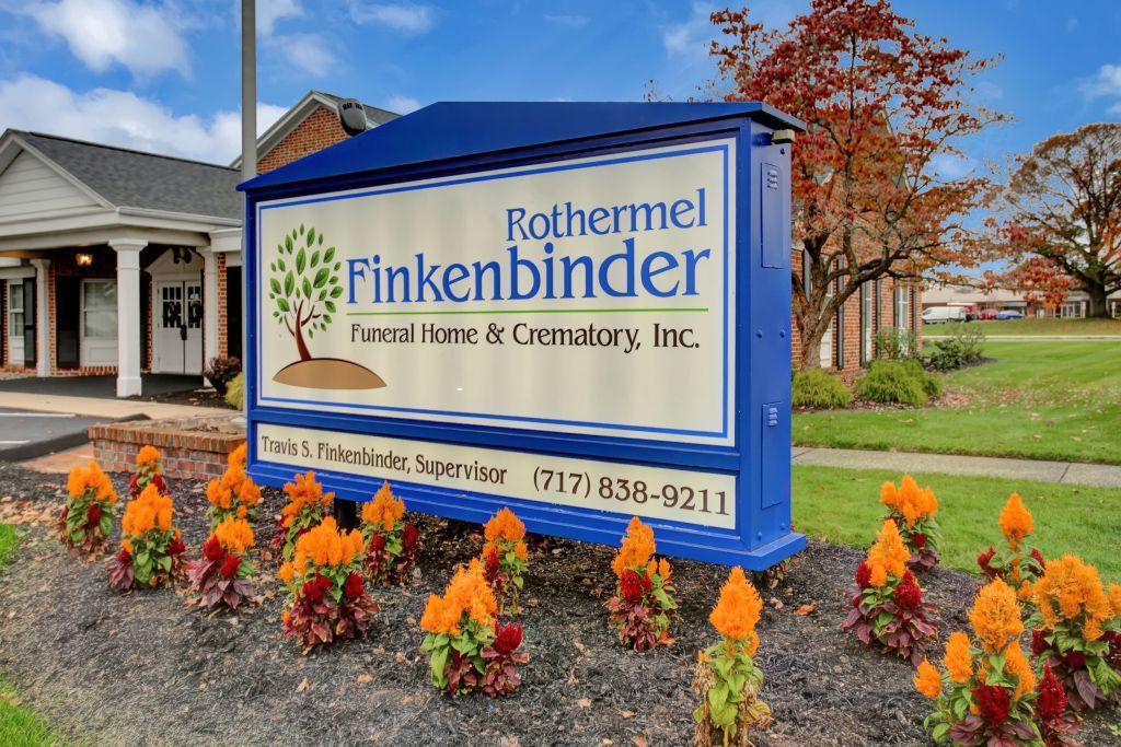 A sign for rothermel finkenbinder is surrounded by flowers