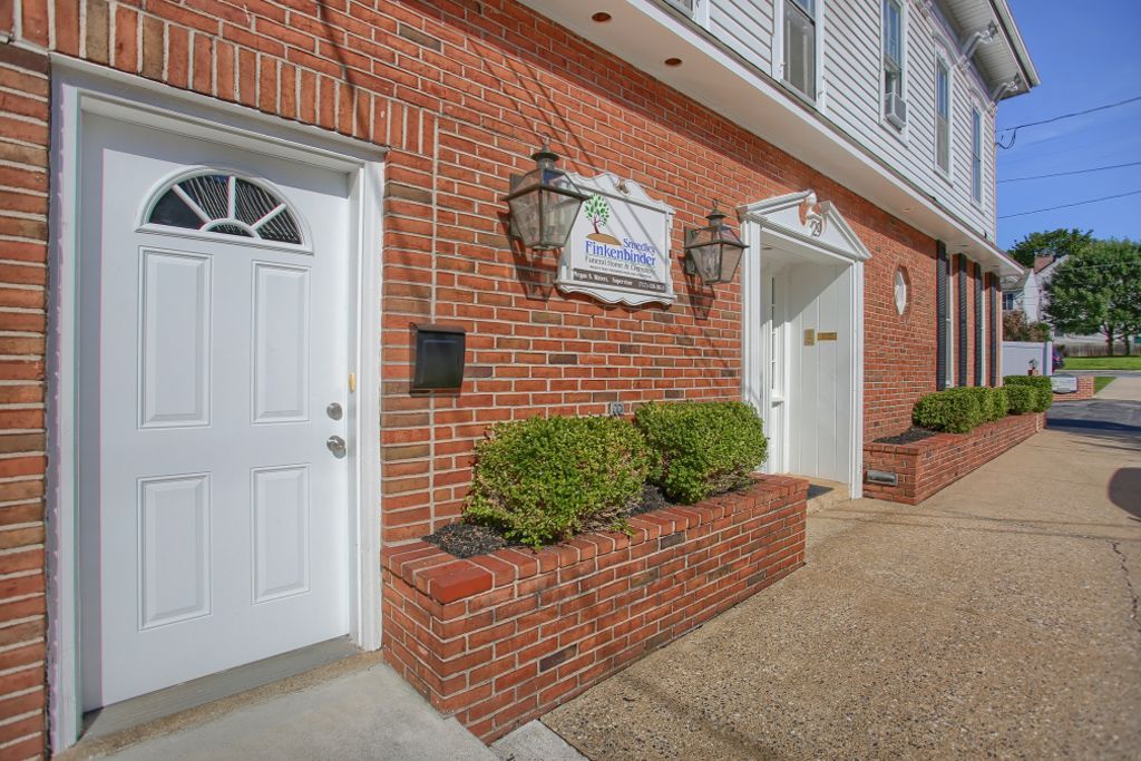 A brick building with two white doors and a sign on the side of it.