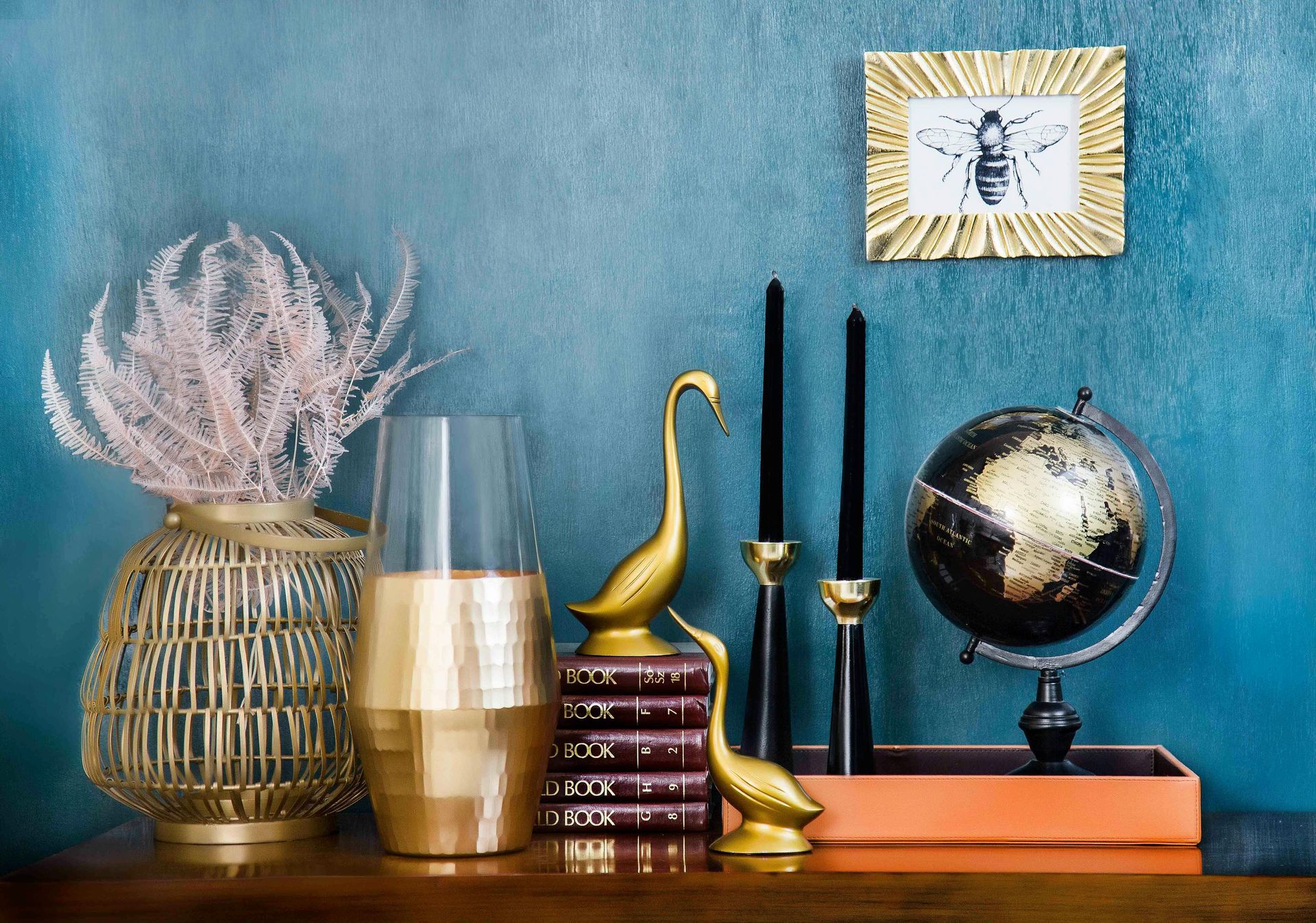 A table with a globe , vases , candles and a picture on it.