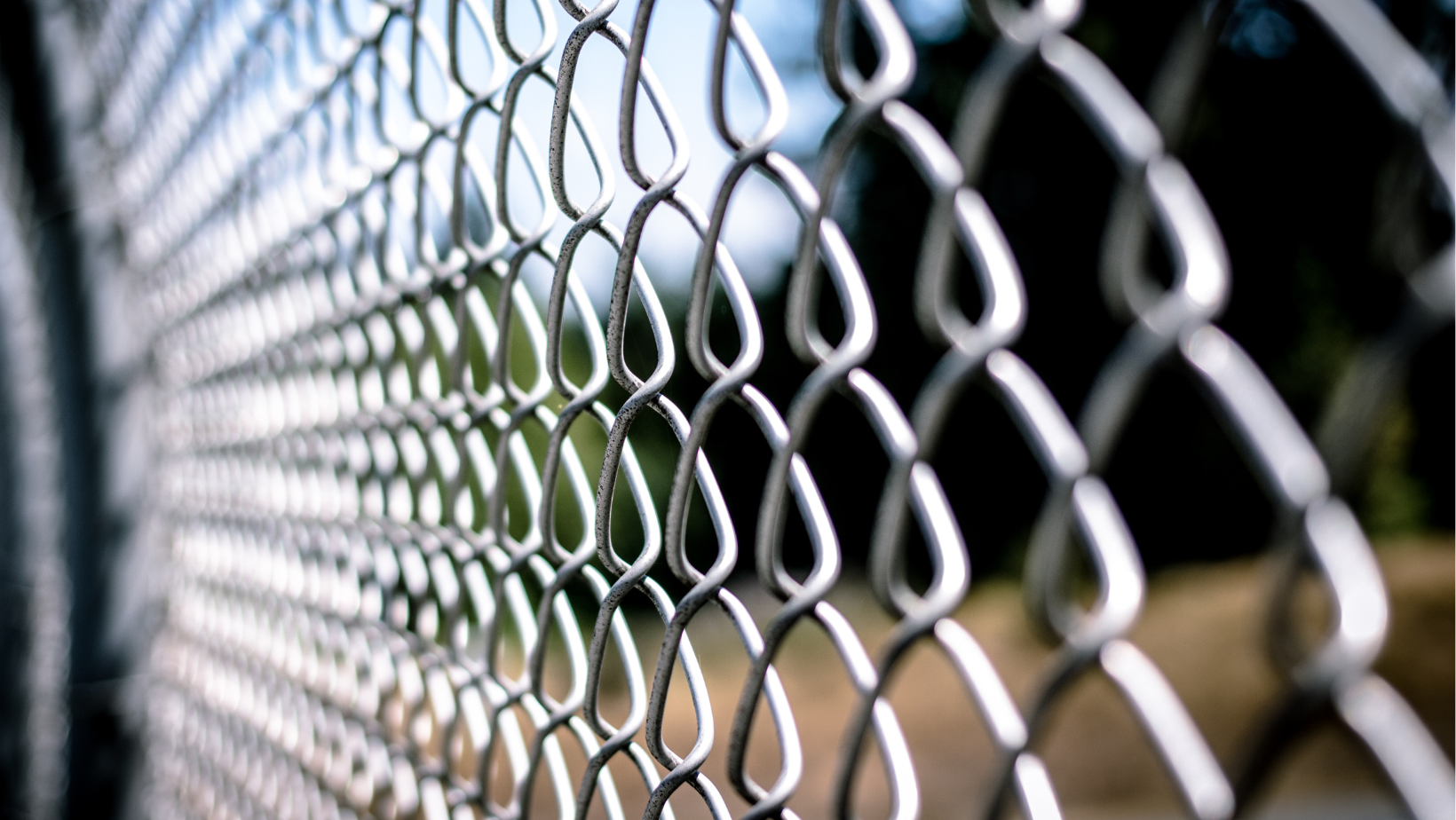 A close up of a chain link fence with a blurry background.