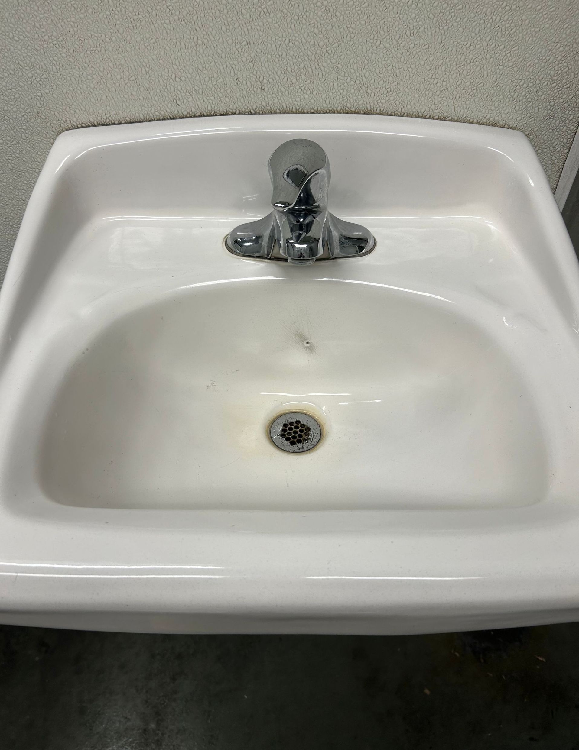 cleaning workplace place bathrooms.White porcelain sink with chrome faucet, viewed straight-on.