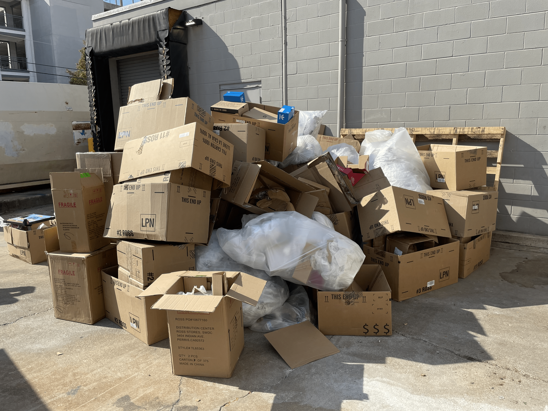 a pile of cardboard boxes and plastic bags in a parking lot .