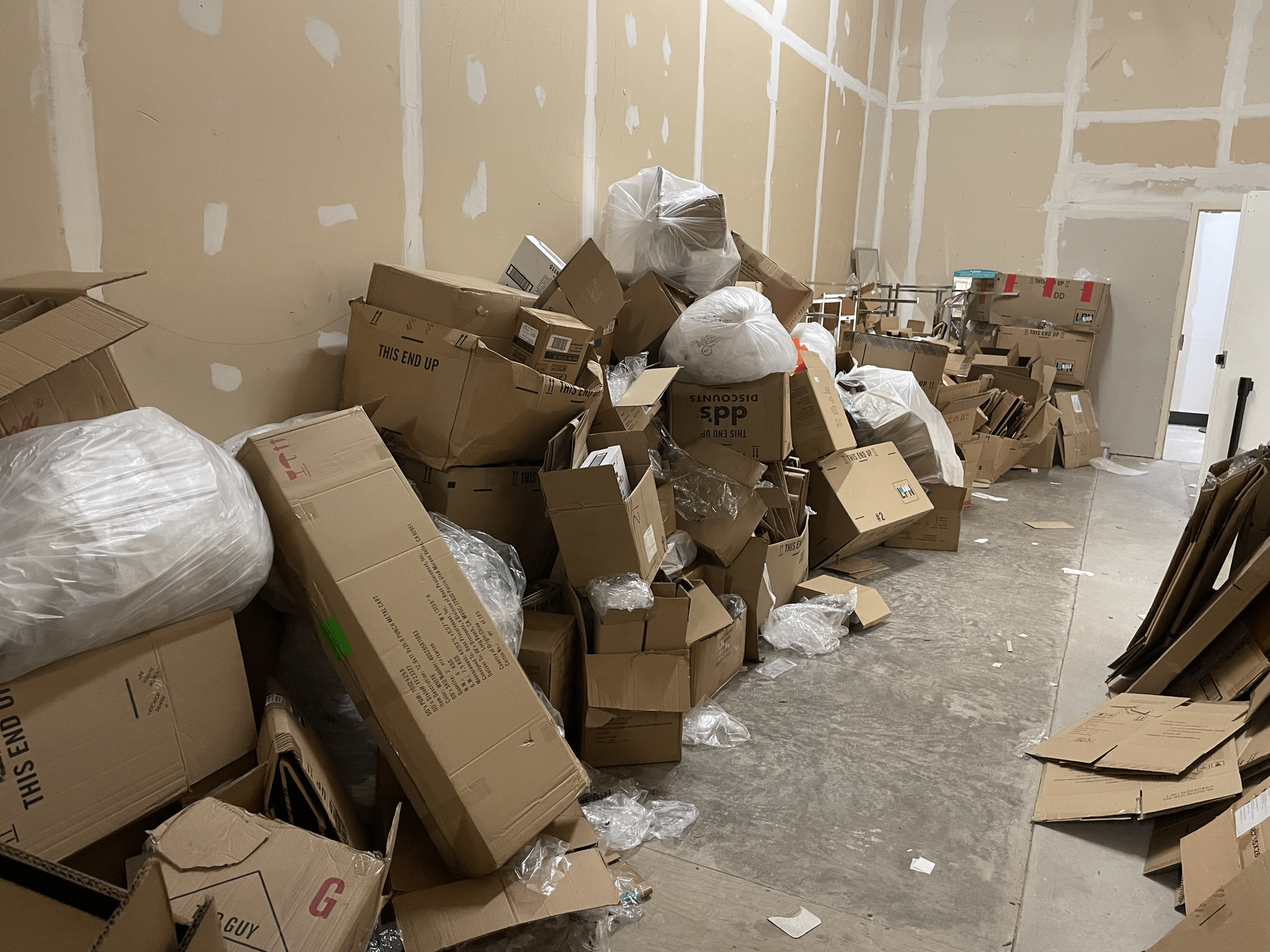 a room filled with lots of cardboard boxes and plastic bags .