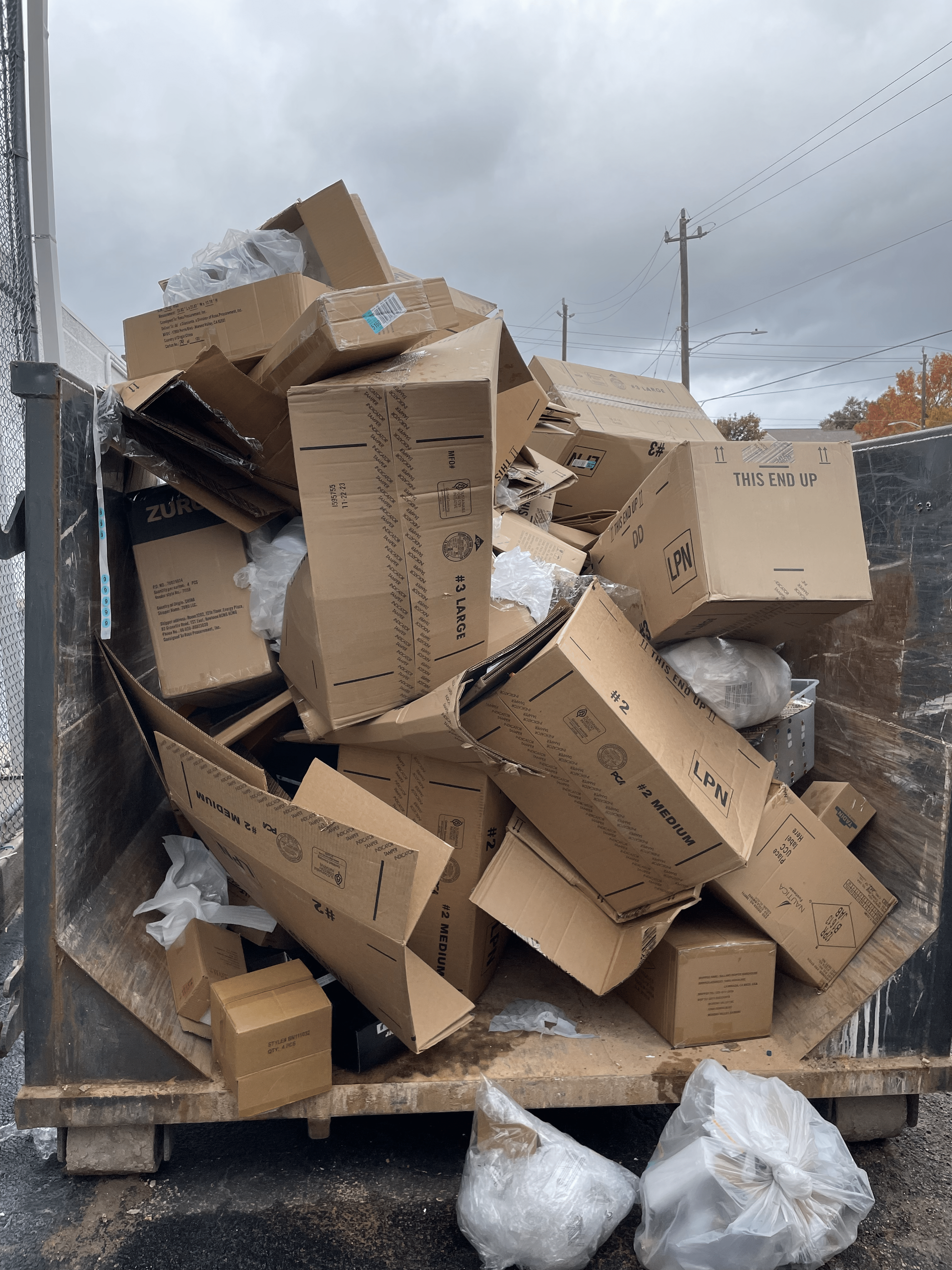 a dumpster filled with cardboard boxes and plastic bags .