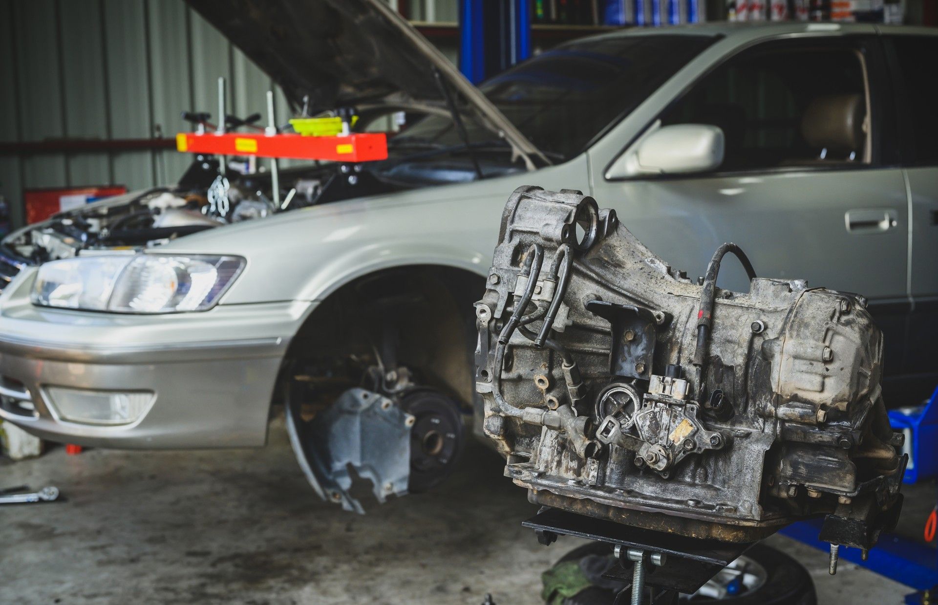 A car engine is being removed from a car in a garage.