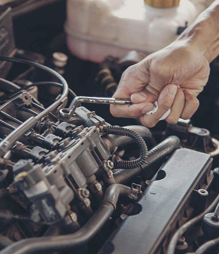 A person is working on a car engine with a wrench.