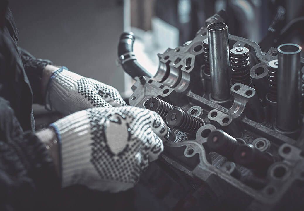 A man wearing gloves is working on a car engine.