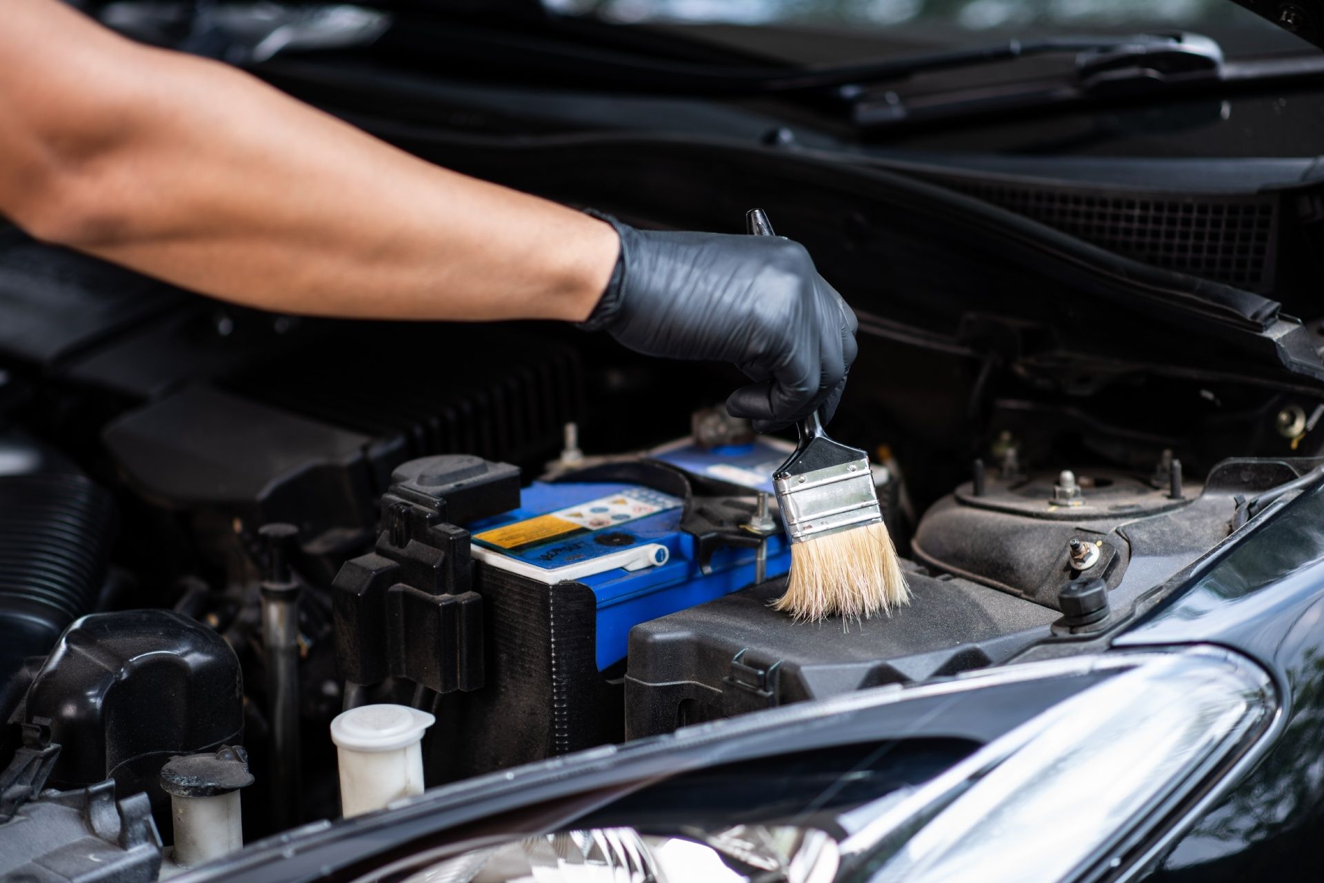 A person is cleaning a car battery with a brush.