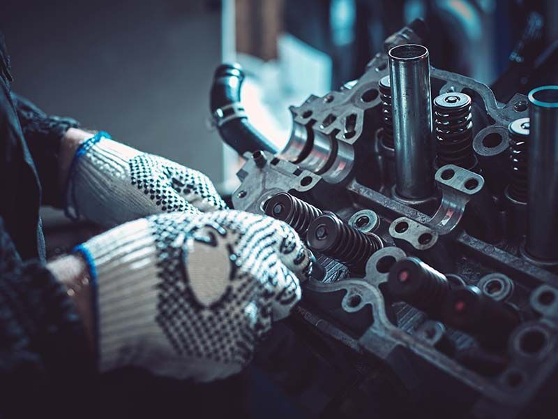 A person wearing gloves is working on a motorcycle engine.