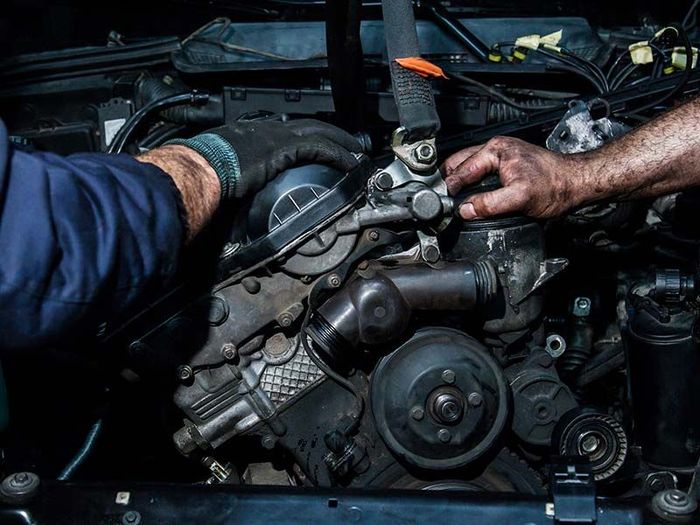 A man is working on the engine of a car.