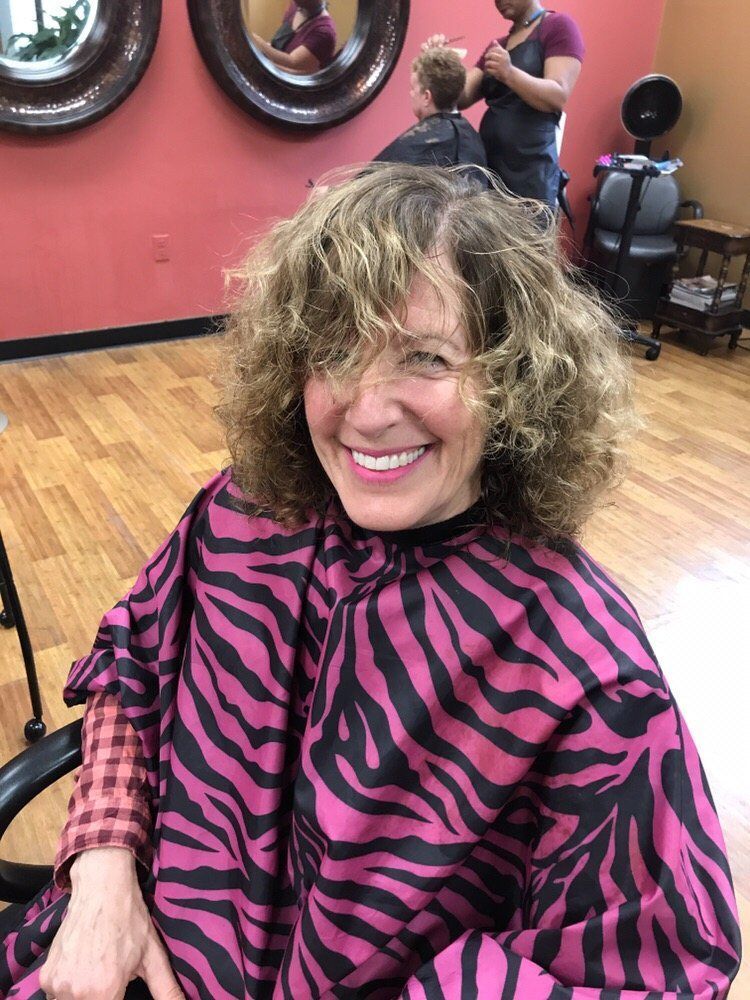 Hair styling tools and products on beige fabric.