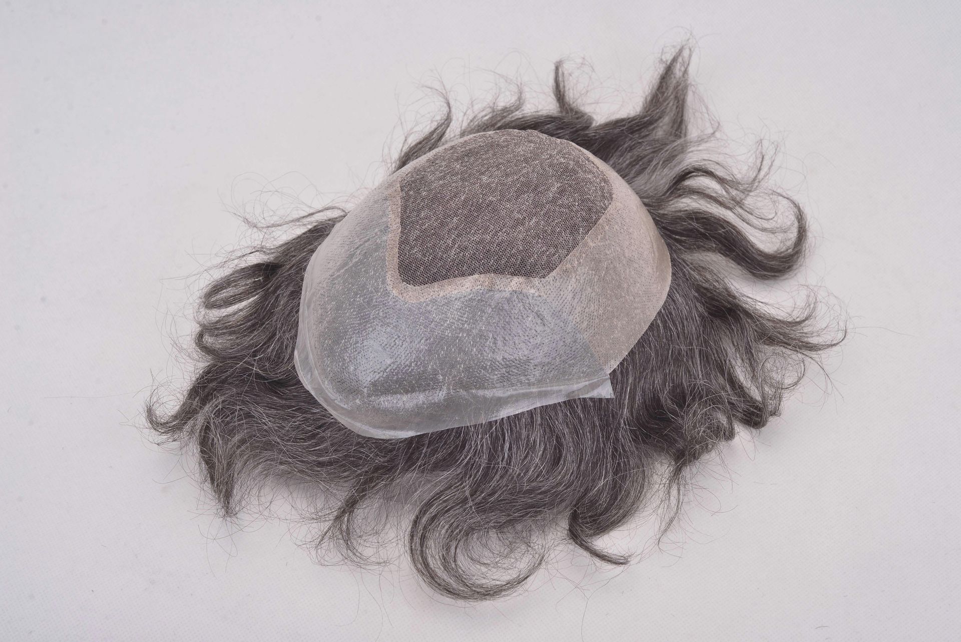 Hair replacement system with gray synthetic hair and a skin-colored cap.