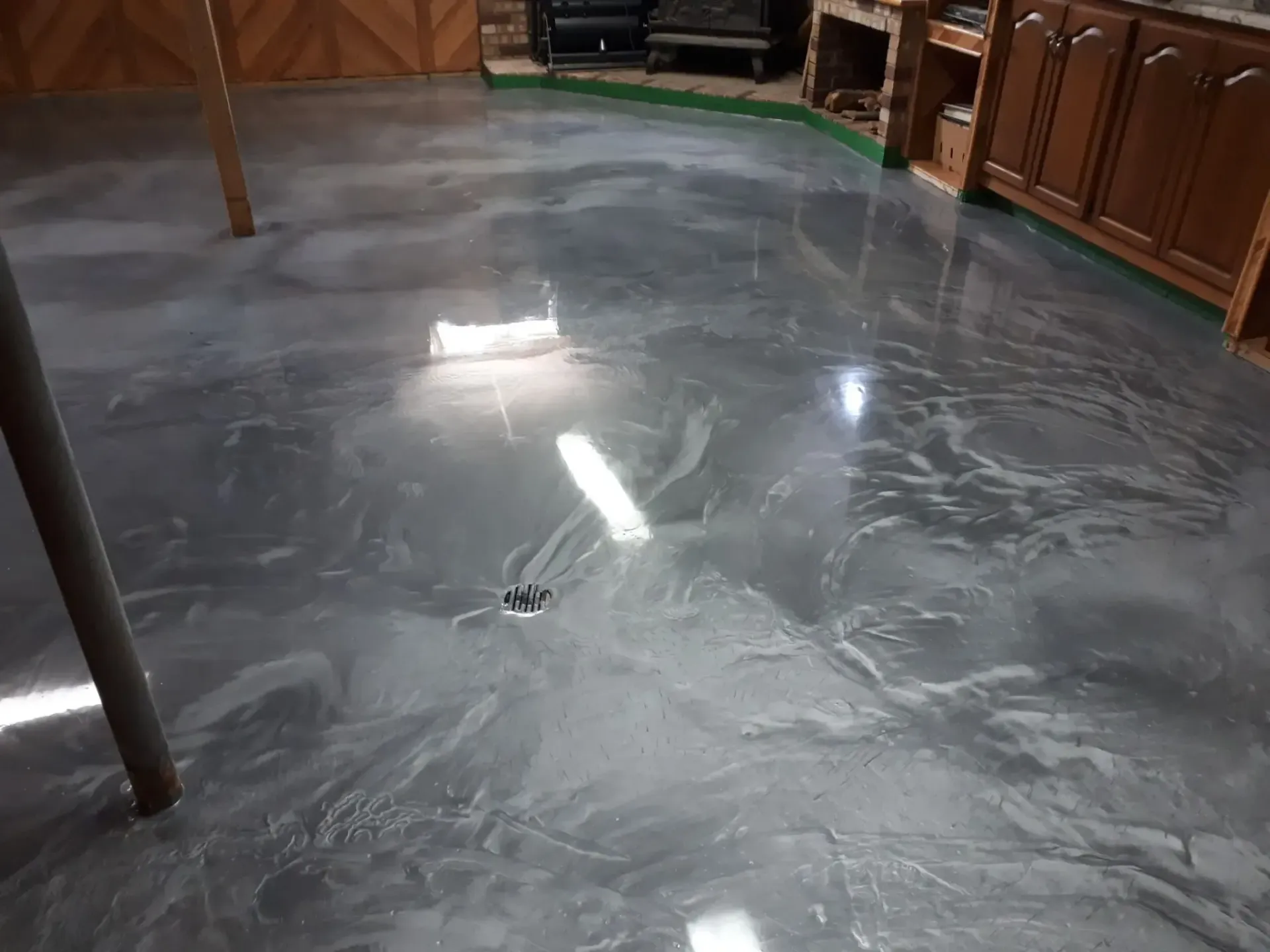 A shiny metallic floor in a basement with wooden cabinets.
