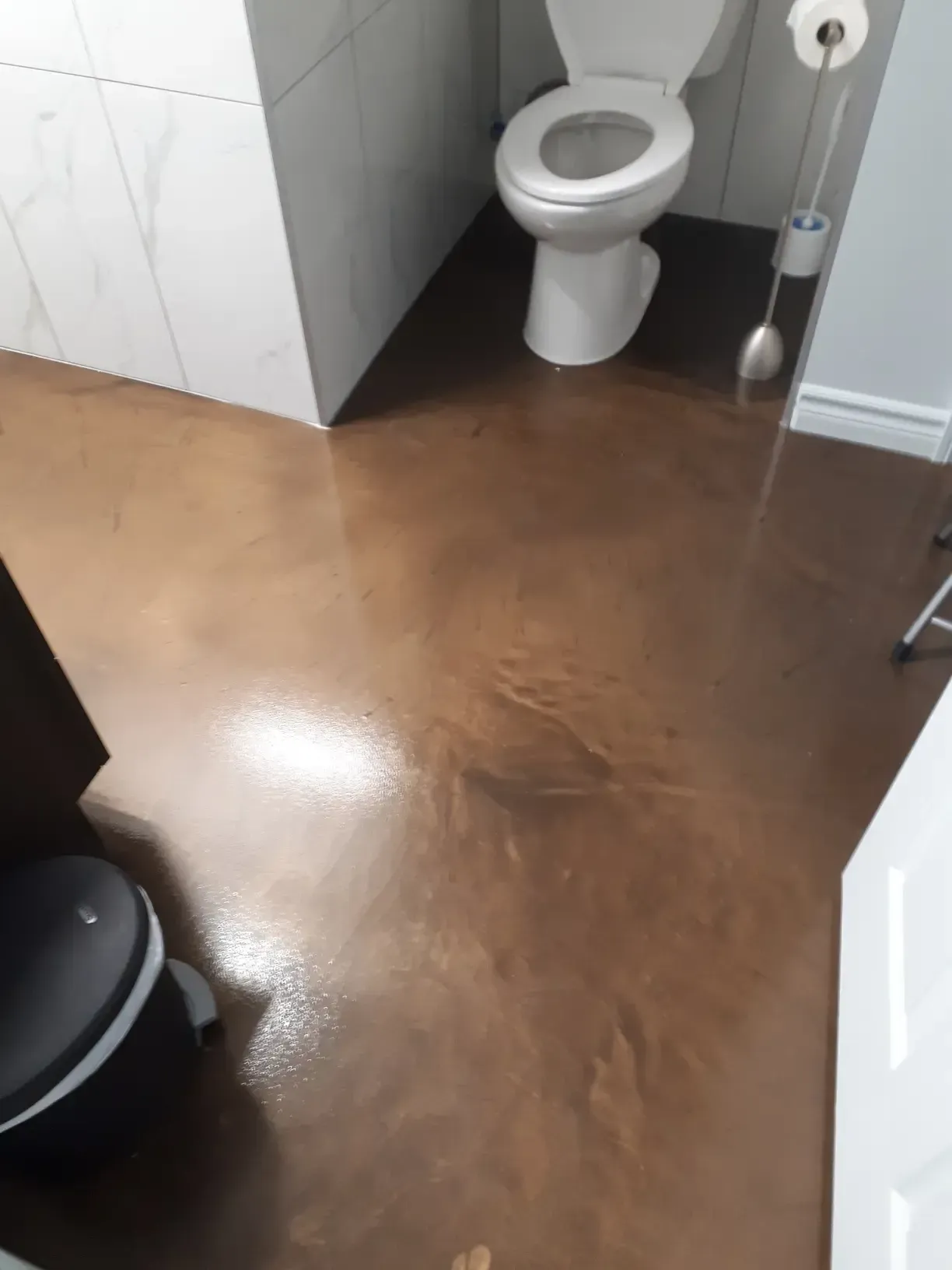 A bathroom with a toilet and a trash can