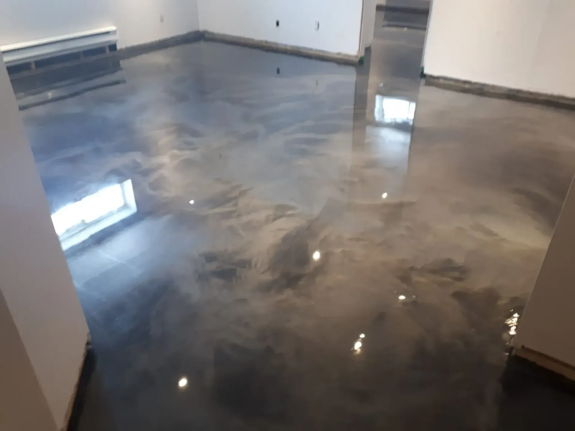 A room with a shiny metallic floor and white walls.