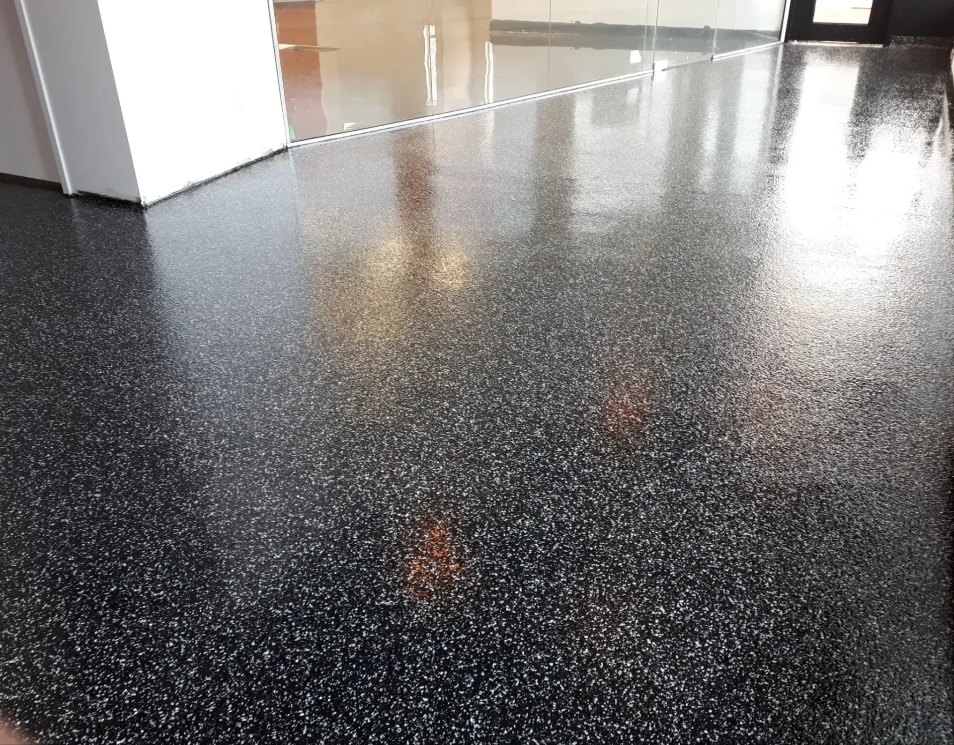Black speckled epoxy floor with shiny, reflective surface.