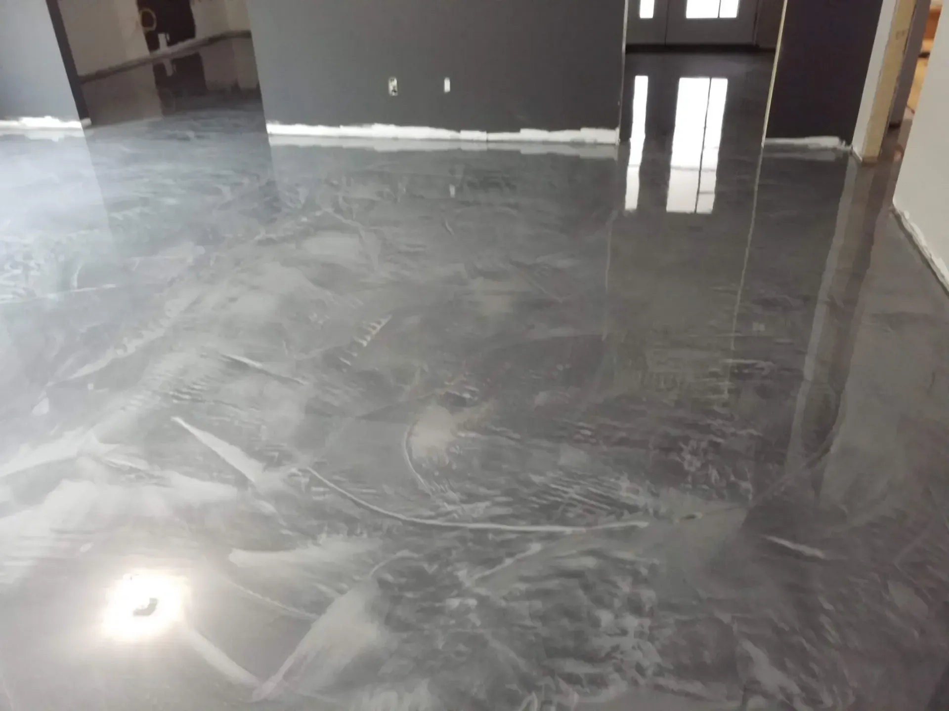 A shiny metallic floor in a living room with a reflection of a window.