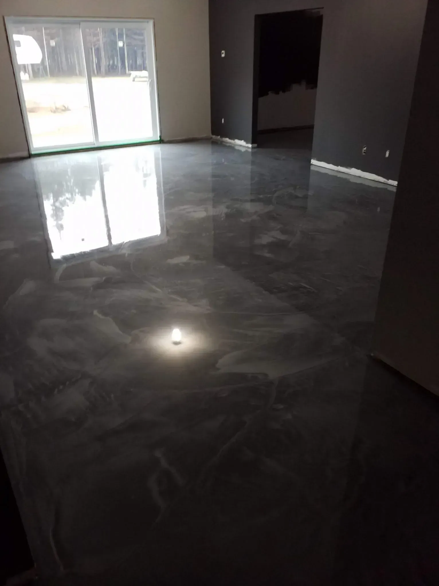 A living room with a shiny metallic floor and a sliding glass door.