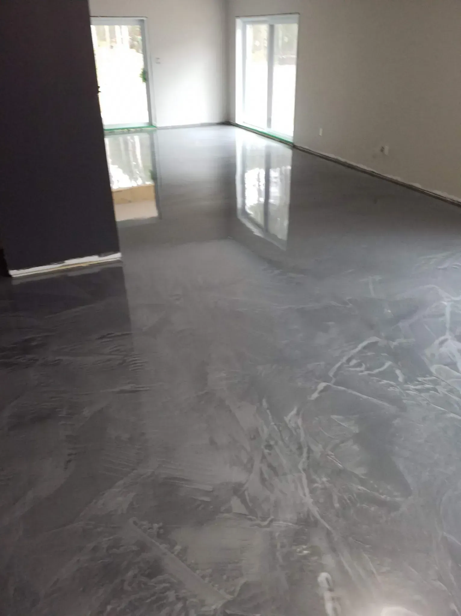 A living room with a shiny metallic floor and sliding glass doors.