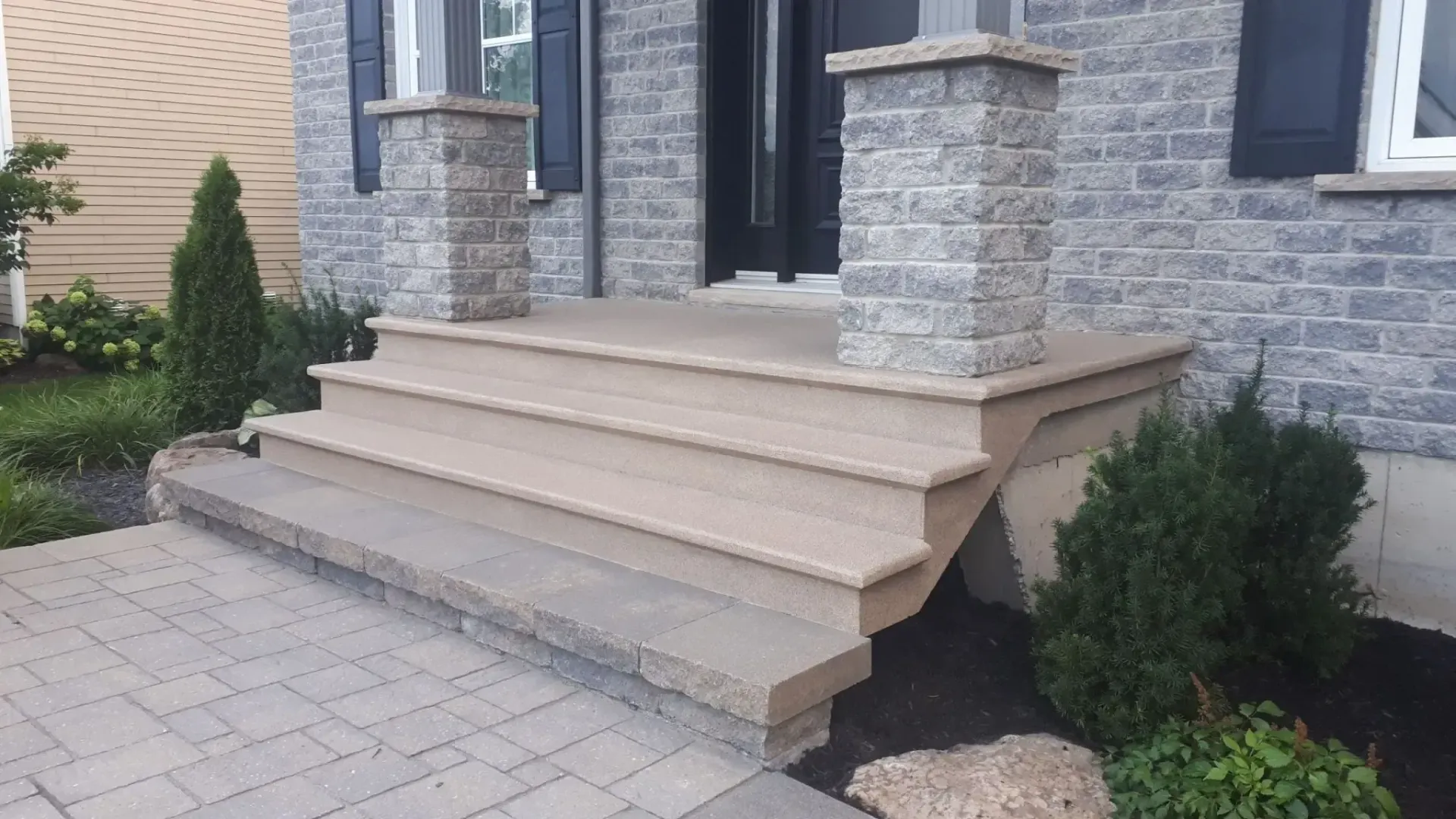 Stone steps and porch leading to a home with brick facade; includes pillars.