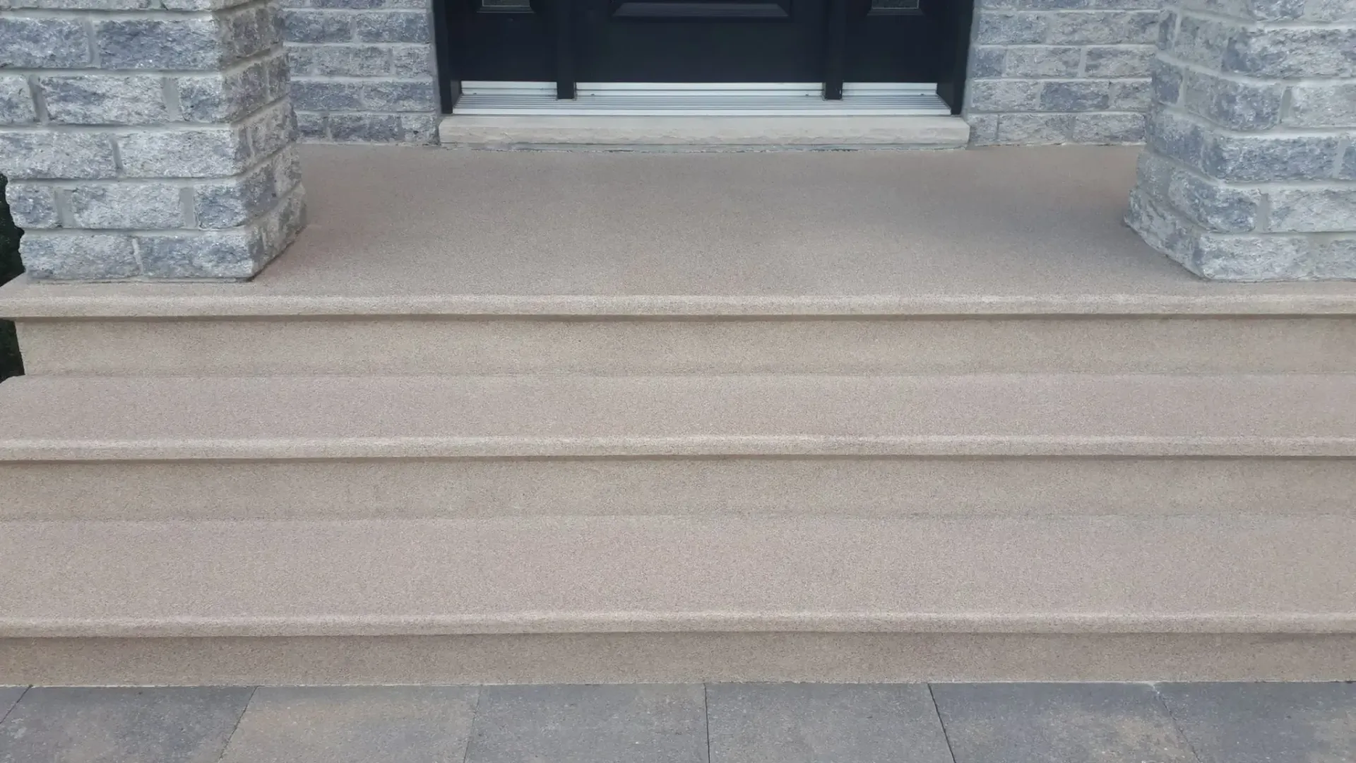 Stone steps leading to a front door, with matching stone columns.