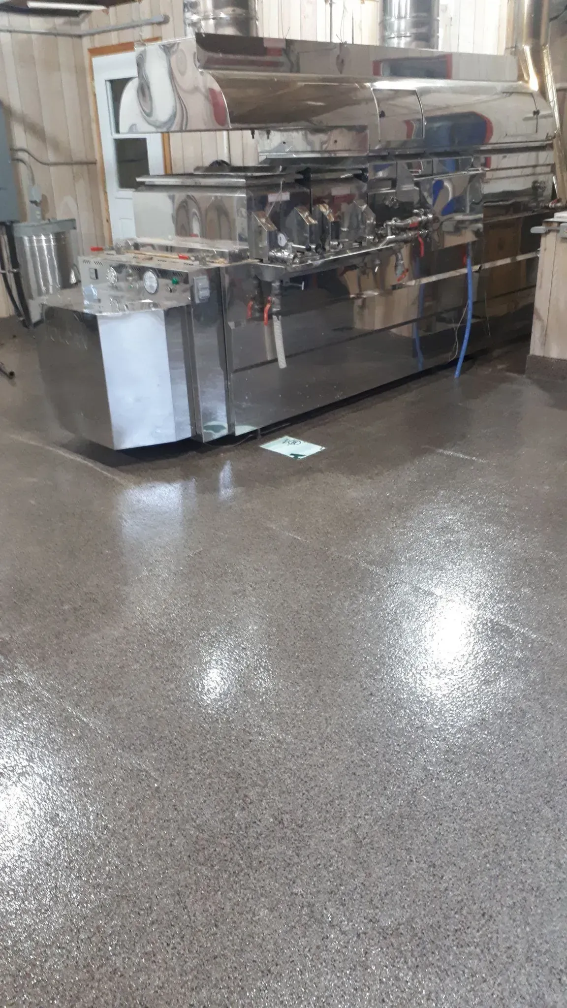 Stainless steel industrial machine in a wet, shiny room.