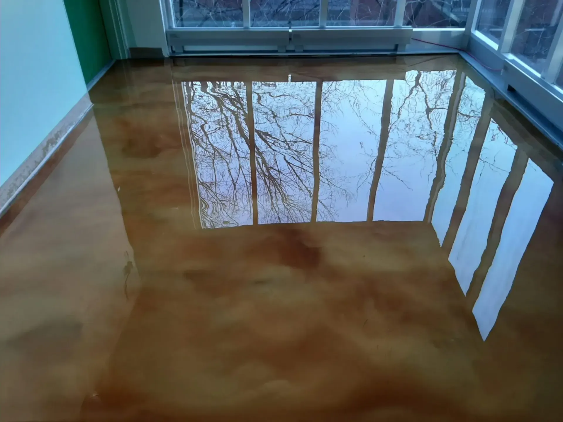 A room with a shiny floor and trees reflected in it
