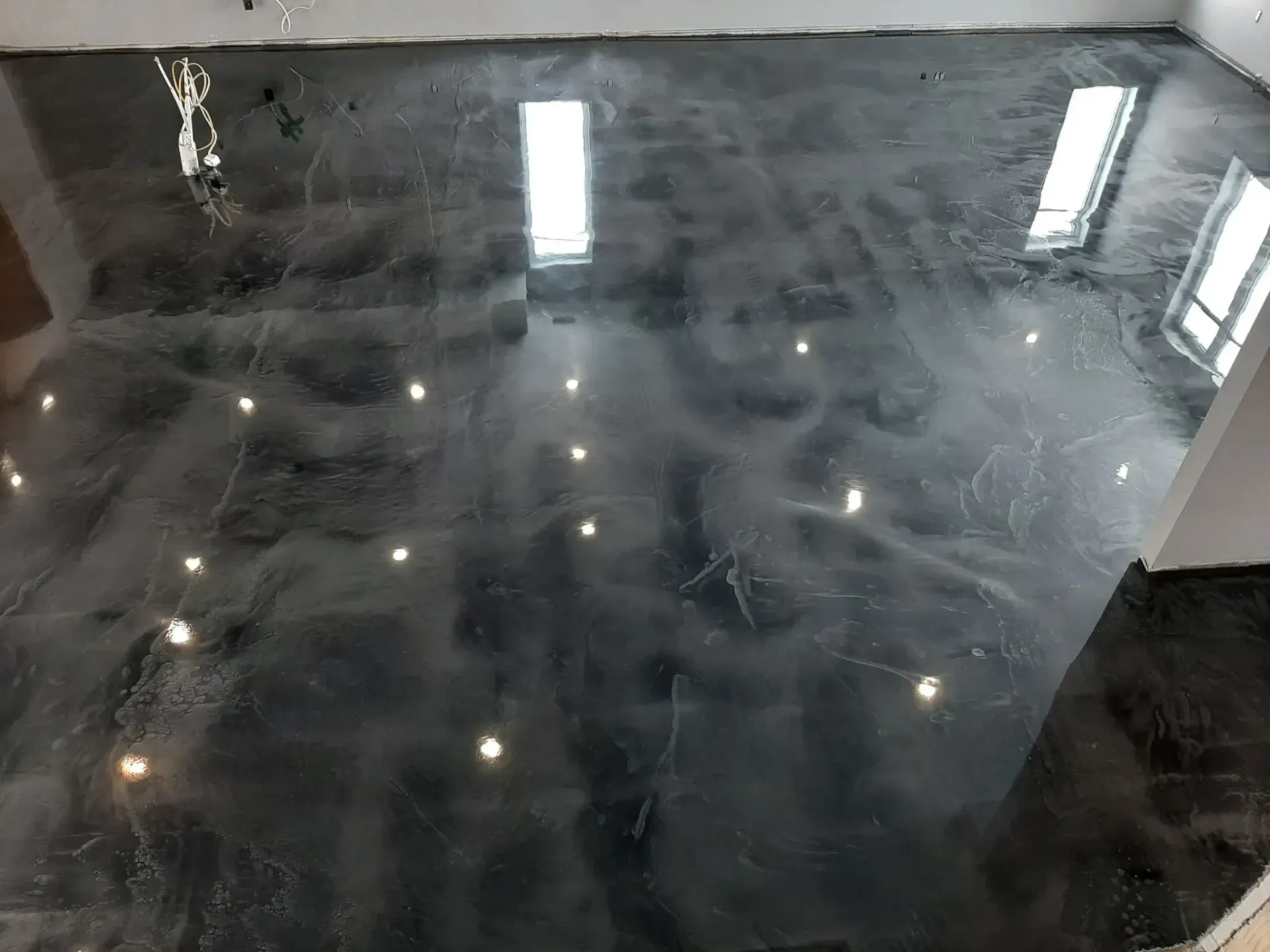 A black and silver epoxy floor in a room with a lot of windows.