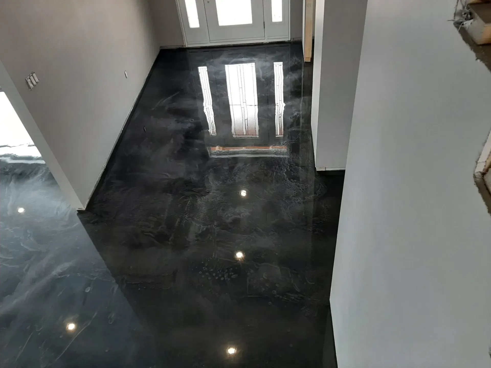 A hallway with a black floor and a white door.