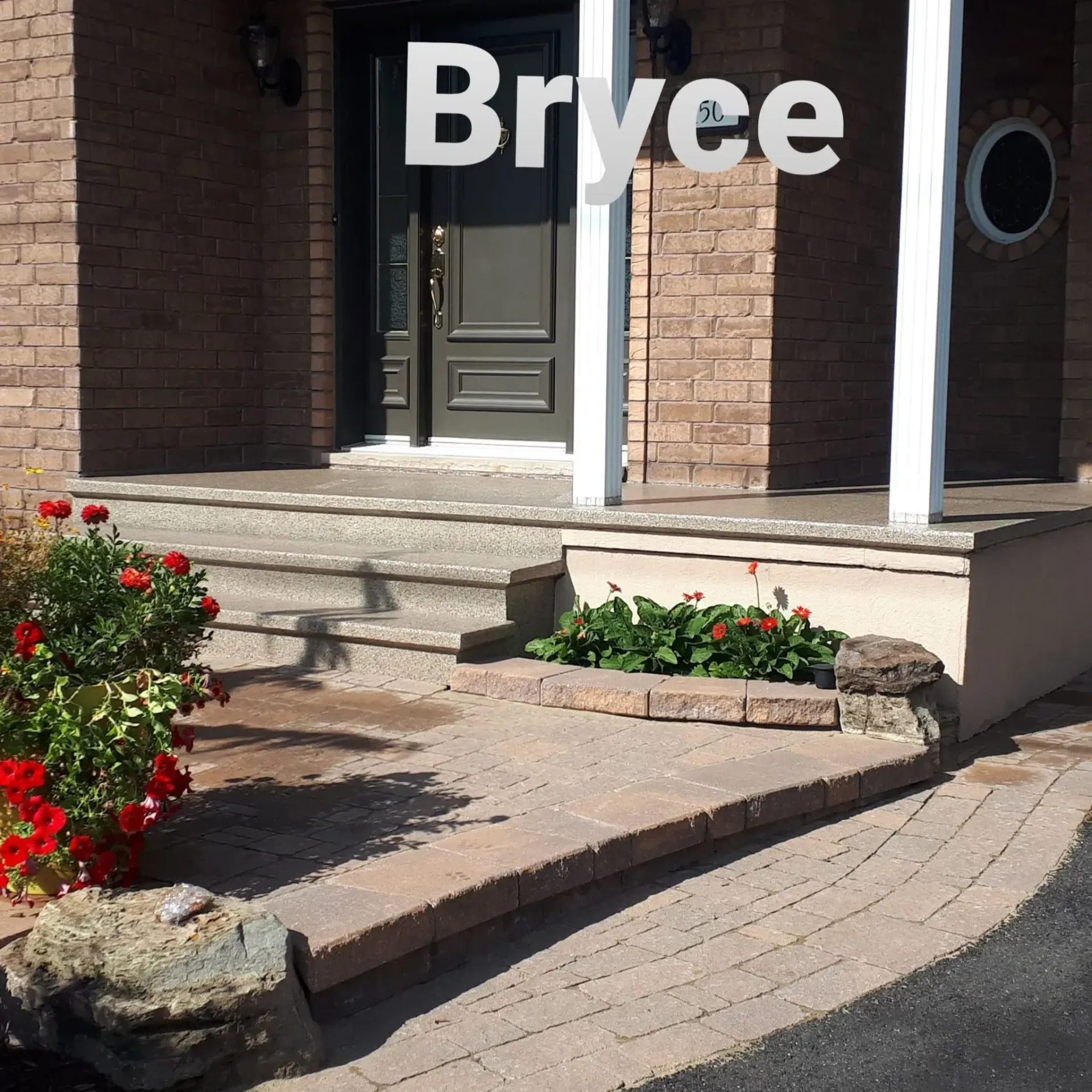 A home's entrance with steps and a brick facade, featuring a red door, flowers, and the name 