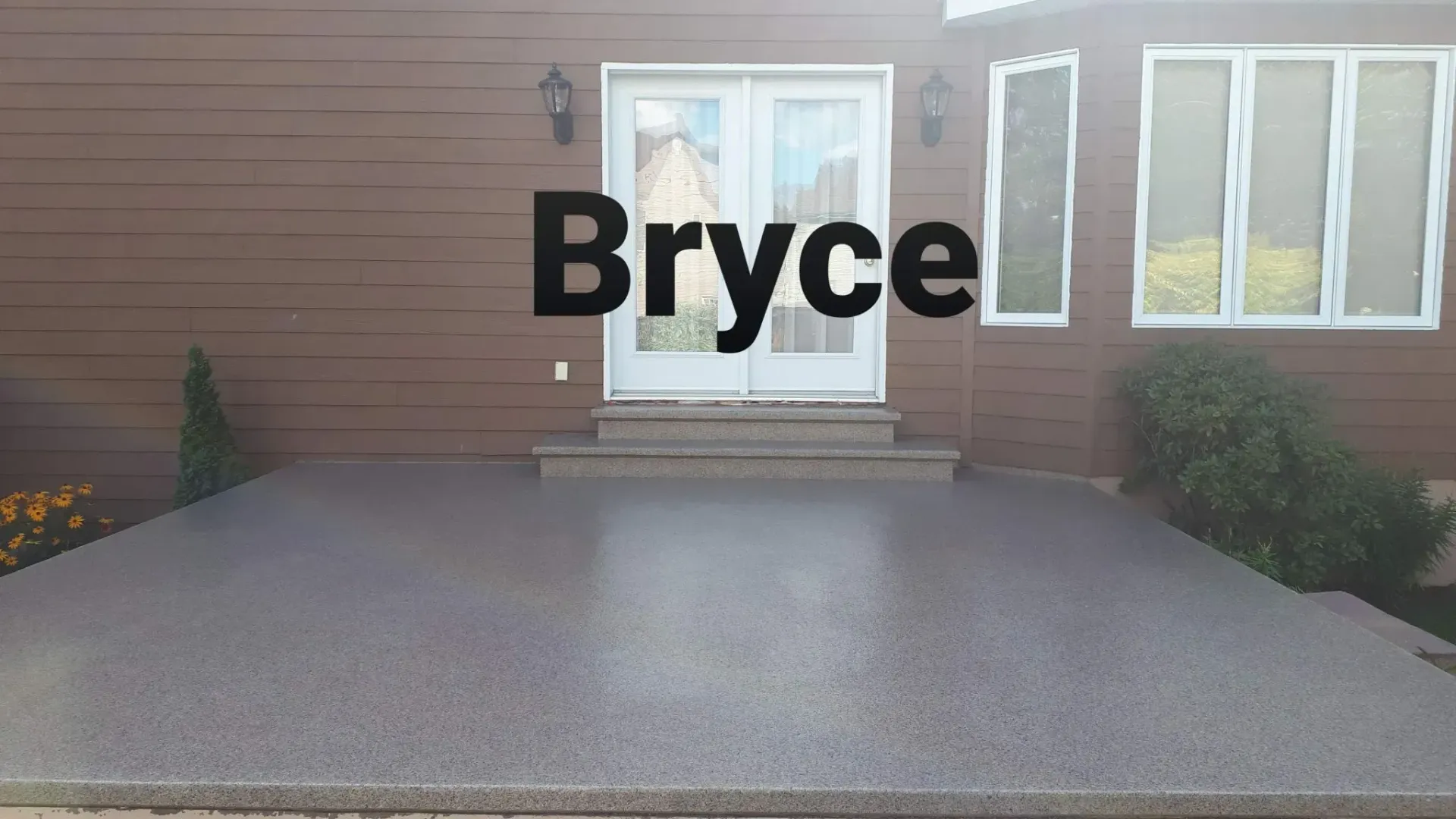 A house with a polished concrete patio, double doors, and the name 