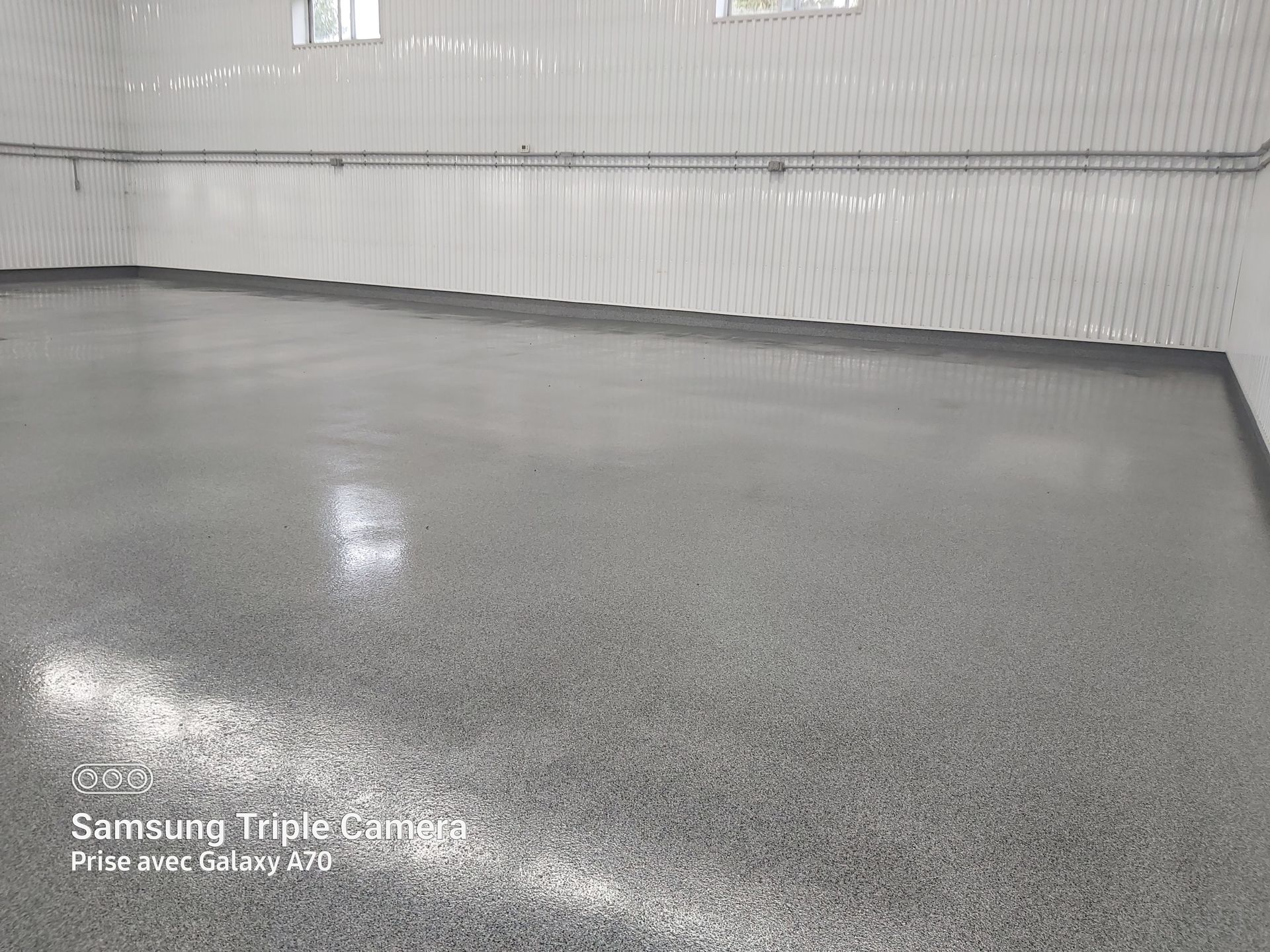 Gray speckled epoxy floor in a white-walled interior with overhead lighting.