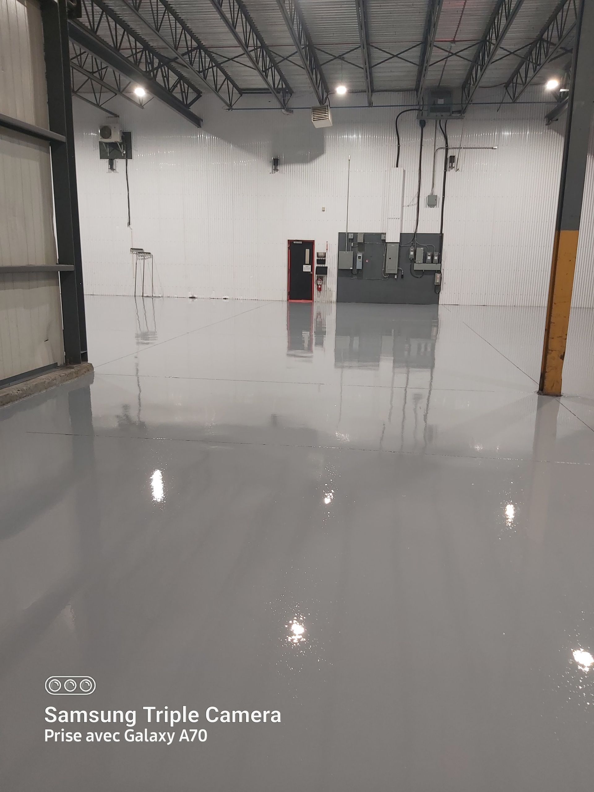 Empty industrial warehouse with a smooth, gray epoxy floor.