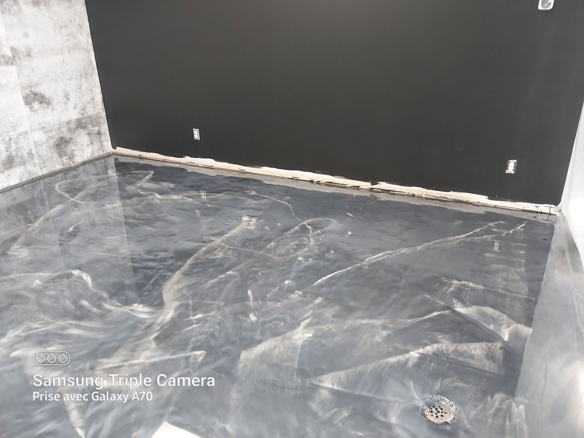 Metallic epoxy floor in a room with black and gray walls.