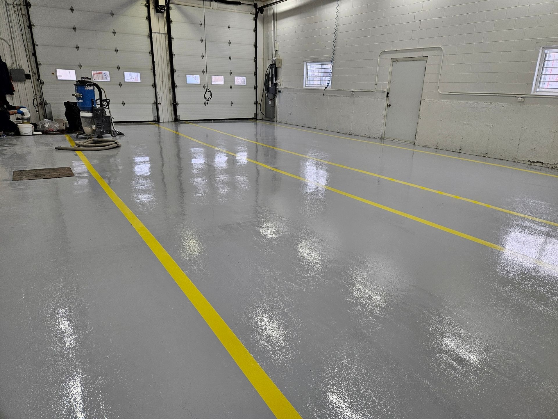 Shiny gray epoxy floor with yellow lines in a garage.