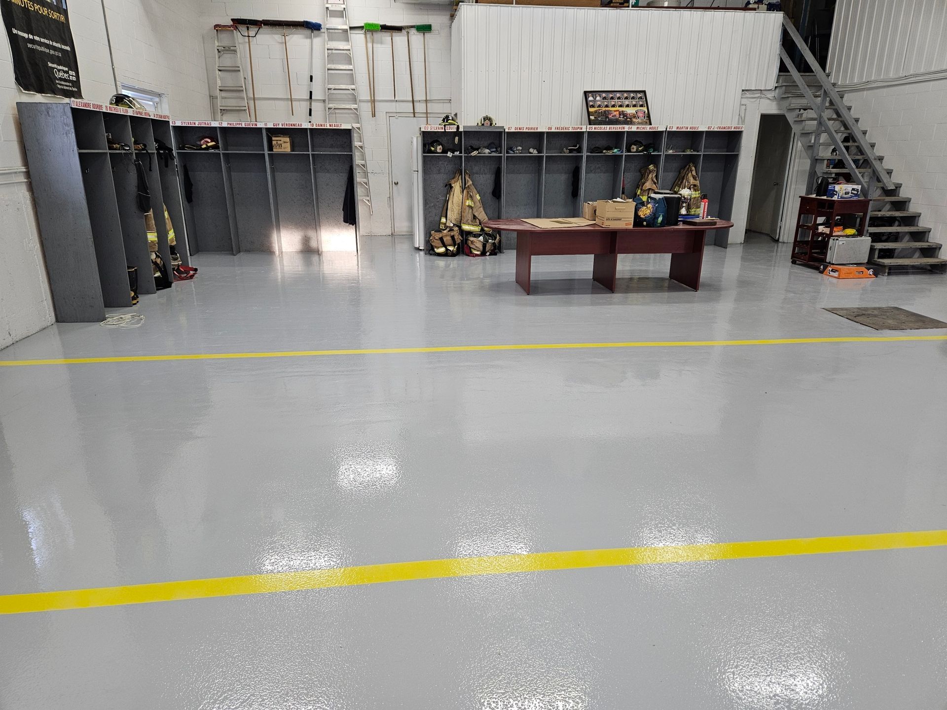 Interior view of a fire station with lockers, a desk, and a staircase, all in a gray and white color scheme.