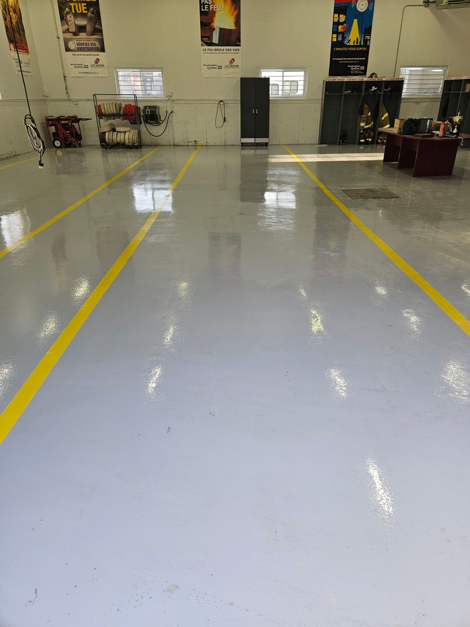 Gray concrete floor with yellow lines in a garage or workshop. Interior with cabinets, and equipment.